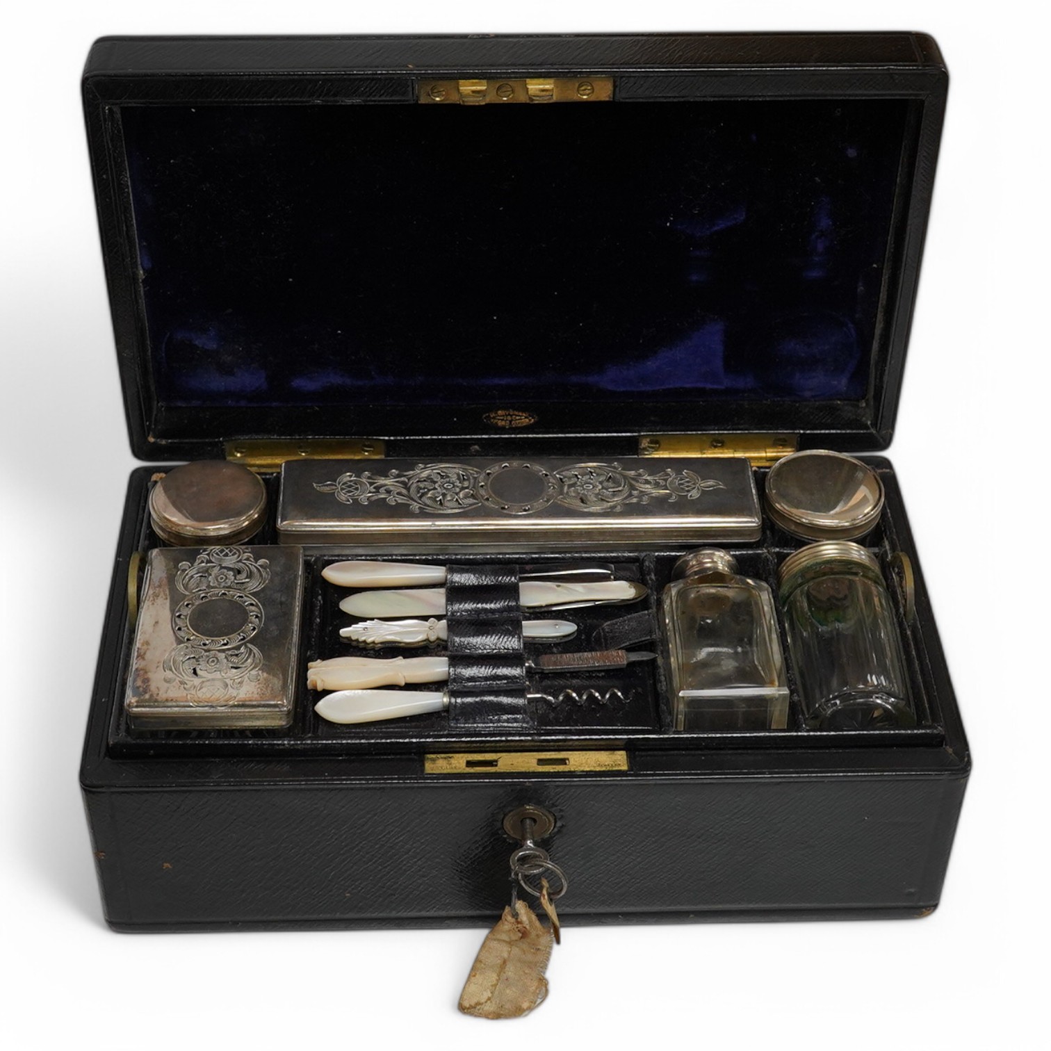 A Victorian leather vanity case with fitted interior to include white metal mounted glass bottles and mother of pearl mounted implements, with key, 27.5cm wide. Condition - fair, handle broken